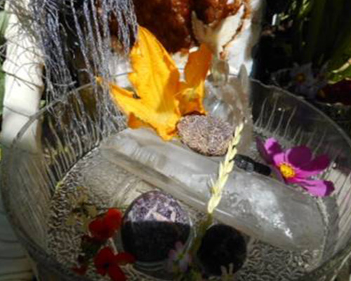 An urchin shell in the water with a large crystal angel and a lepidolite sphere